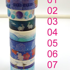 May include: A vertical stack of eight rolls of decorative washi tape, numbered 01 through 08 in pink text. The tapes feature various blue-toned designs including blueberries, bubbles, rabbits, fireworks, flowers, and seagulls on a white background.