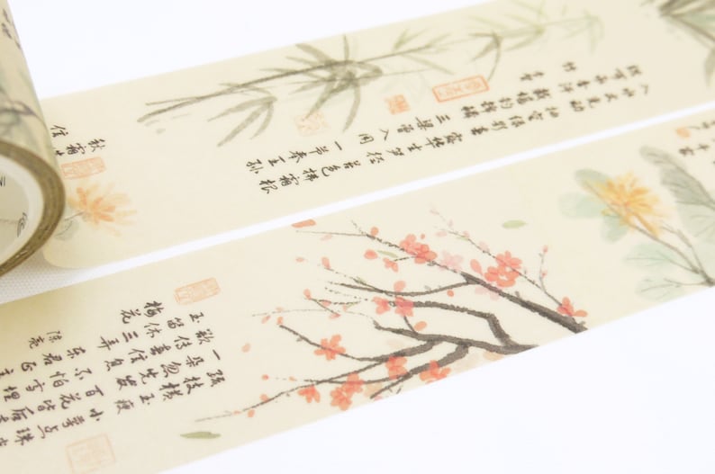May include: A roll of decorative washi tape with a beige background and a delicate floral design. The tape features a branch of pink blossoms, a bamboo plant, and a yellow flower. The tape also includes text in Japanese characters.