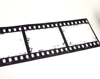 Może przedstawiać: Czarno-biały pasek filmu z trzema pustymi klatkami. Pasek filmu jest lekko zużyty i ma ziarnistą fakturę.