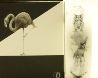 May include: A decorative box and a roll of washi tape. The box has a black and white design with a flamingo illustration. The tape roll shows illustrations of an owl, cat, and deer.