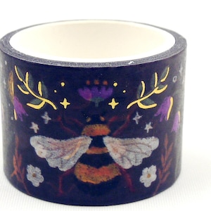 May include: A roll of decorative washi tape with a dark blue background, showcasing a bee, flowers, and foliage illustration. The bee has detailed wings and a yellow and black body. The tape has a white interior.
