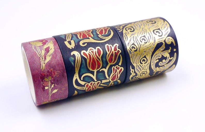 Pu&ograve; includere: Quattro rotoli di nastro washi decorativo con motivi dorati e floreali su sfondo blu scuro. Il nastro &egrave; arrotolato e impilato uno sopra l'altro.