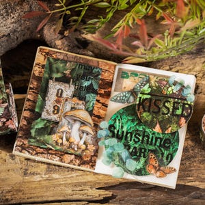 Peut inclure: Un journal d&eacute;coratif sur le th&egrave;me de la nature. Le journal pr&eacute;sente une illustration de champignons, des accents de papillons et les mots "Kissed Sunshine Are". Les pages ont une texture semblable &agrave; du bois, avec des tons verts et bruns.