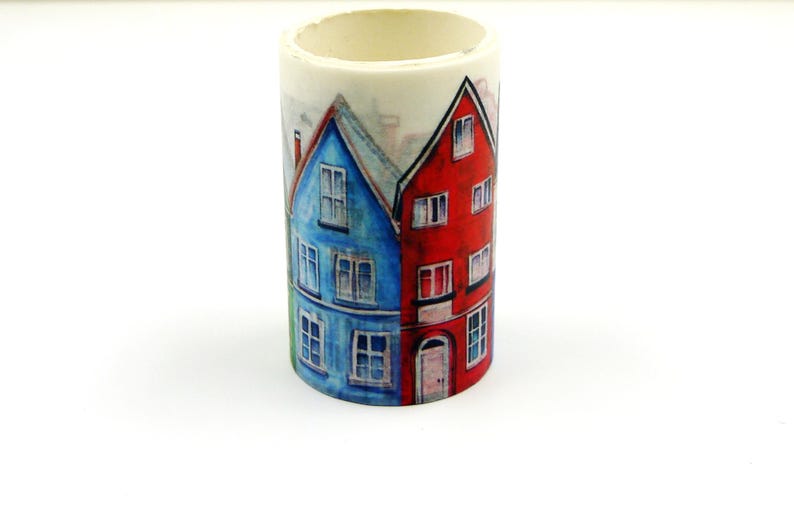May include: A cylindrical washi tape roll featuring a watercolor illustration of colorful houses. The houses are painted in shades of blue, red, and green, with white window details. The tape is ideal for crafts and decorative projects.