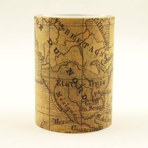 May include: A roll of washi tape featuring a vintage map design. The tape is tan with a detailed black map print, including text such as "Mexique" and "Etats-Unis". The tape is cylindrical and stands upright against a white background.
