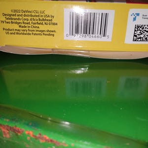 Op de afbeelding: Een close-up van een gele productdoos met een barcode en tekst. De tekst bevat copyrightinformatie, bedrijfsgegevens en de zin "Made in China."