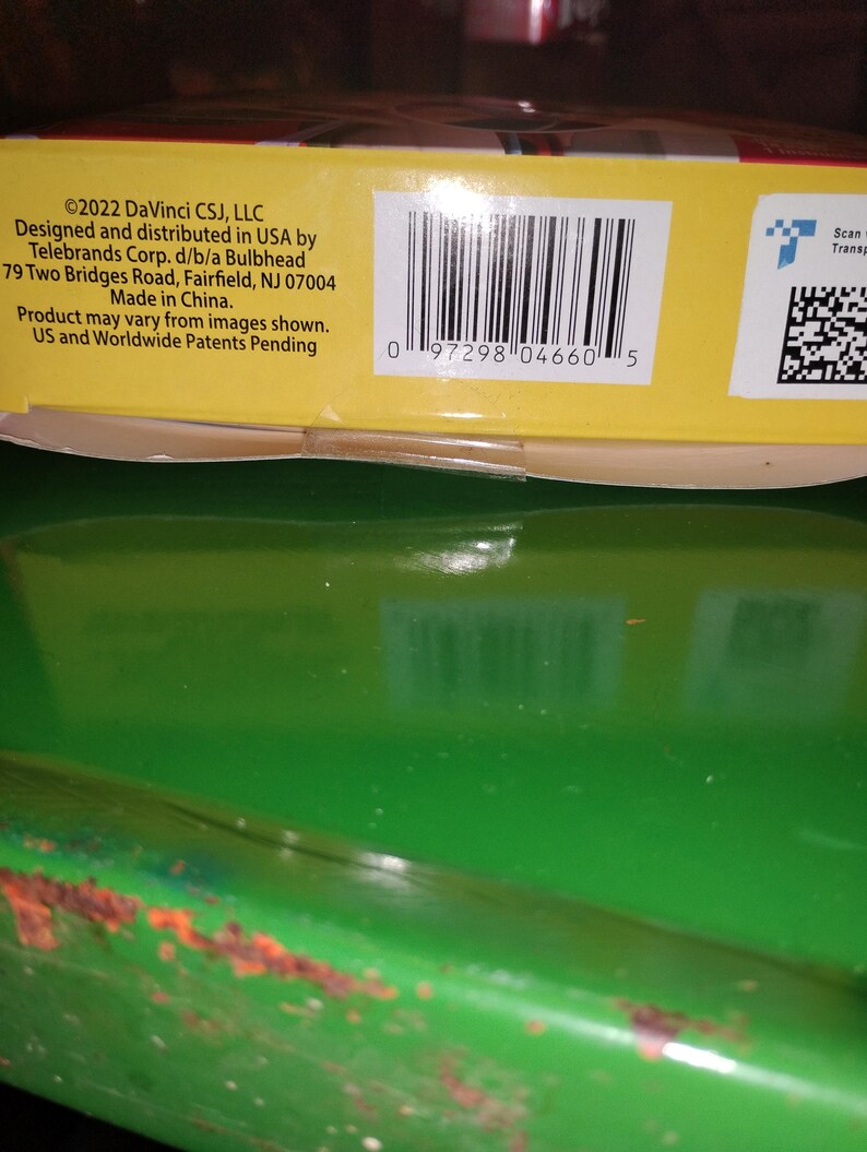 Op de afbeelding: Een close-up van een gele productdoos met een barcode en tekst. De tekst bevat copyrightinformatie, bedrijfsgegevens en de zin "Made in China."
