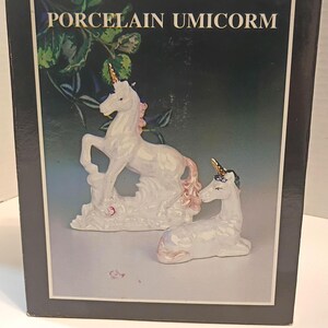 May include: A box featuring a porcelain unicorn figurine set. The figurines are white with gold horns and pink accents. The box has the words "PORCELAIN UMICORM" in white text.