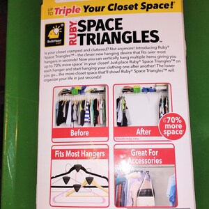 Op de afbeelding: Een gele en rode doos voor Ruby Space Triangles, een hulpmiddel voor kastorganisatie. De doos bevat tekst en afbeeldingen die laten zien hoe het product de kastruimte vergroot. Het product beweert de kastruimte te verdrievoudigen.