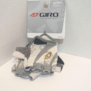 May include: Gray and white Giro cycling gloves with a Super Fit Engineered design. The gloves have a medium size and are fingerless. The Giro logo is visible on the gloves and the packaging.