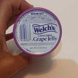 Puede incluir: Primer plano de un tarro de gelatina de uva Concord Welch's morado. La etiqueta incluye el nombre de la marca, el nombre del producto y la informaci&oacute;n nutricional. El peso neto es de 283 g.