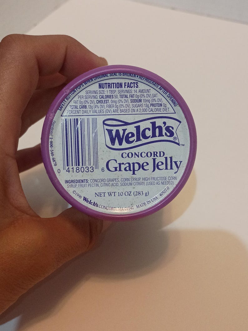 Puede incluir: Primer plano de un tarro de gelatina de uva Concord Welch's morado. La etiqueta incluye el nombre de la marca, el nombre del producto y la informaci&oacute;n nutricional. El peso neto es de 283 g.
