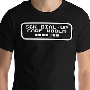 Könnte beinhalten: Schwarzes T-Shirt mit dem Text "56K DIAL-UP CORE MODEM" in weißer Schrift im Retro-Stil. Das Design ist in einem weißen Rechteck eingeschlossen. Das Shirt hat kurze Ärmel und einen Rundhalsausschnitt.