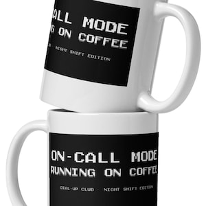 Könnte beinhalten: Zwei weiße Keramikbecher, die übereinander gestapelt sind. Der obere Becher hat den Text "ON-CALL MODE RUNNING ON COFFEE" in Weiß auf einem schwarzen Rechteck. Der untere Becher hat den gleichen Text.
