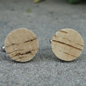 Könnte beinhalten: Ein Paar runde Manschettenknöpfe aus Kork mit natürlicher Holzmaserung.