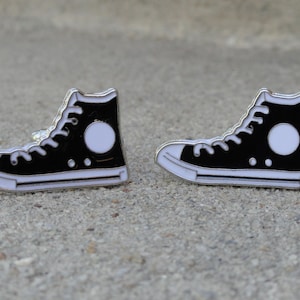May include: A pair of black and white enamel cufflinks shaped like high-top sneakers.