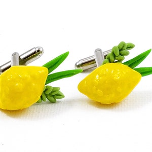 Puede incluir: Un par de gemelos con un limón amarillo con hojas verdes, un símbolo tradicional de la festividad judía de Sucot.