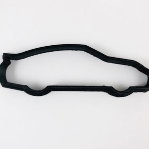 Pode incluir: Cortador de biscoitos de plástico preto em forma de carro.