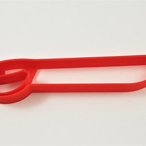 May include: Red plastic cookie cutter shaped like a boat with a rounded front and a flat back.