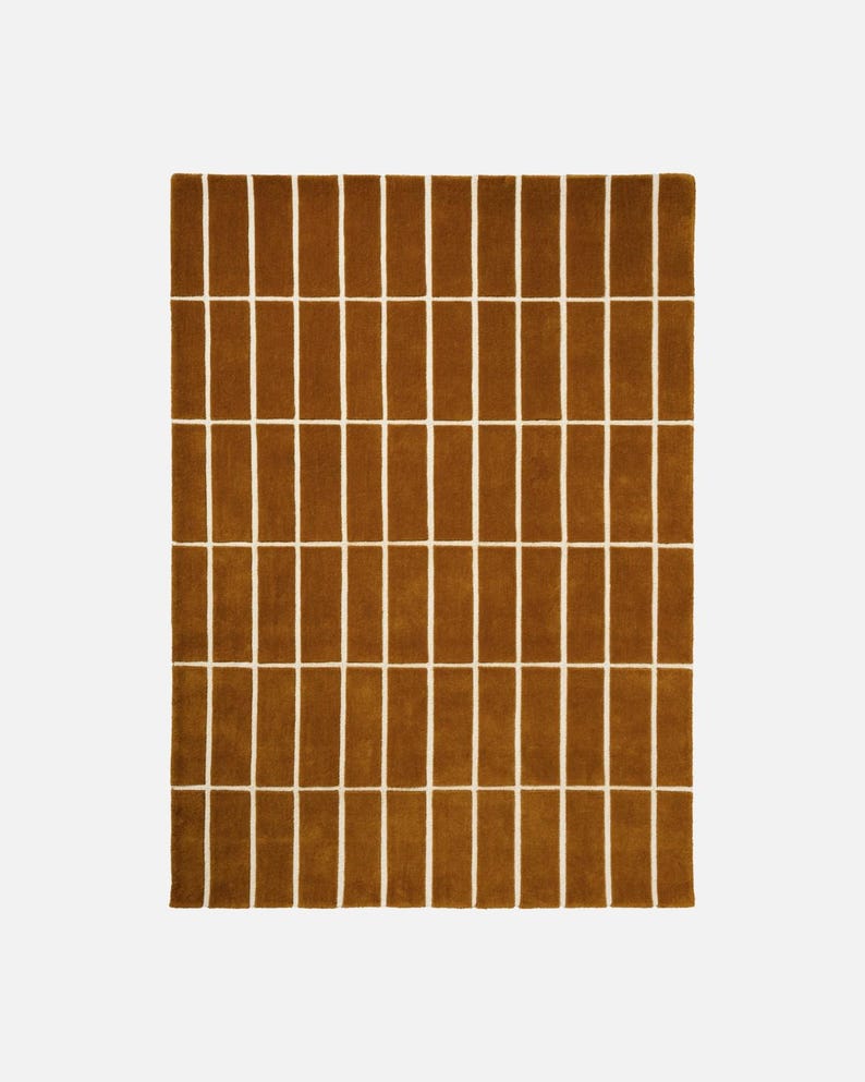 May include: A rectangular brown rug with a repeating pattern of vertical brown rectangles separated by white lines. The rug has a soft, textured appearance and is suitable for a living room or bedroom.