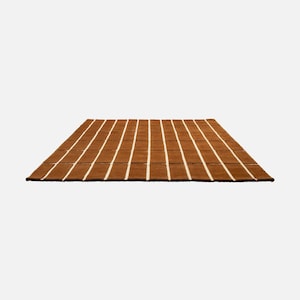 May include: A rectangular brown rug with vertical white stripes. The rug has a textured appearance and is placed on a white background. The rug is a home decor item, suitable for living rooms or bedrooms.