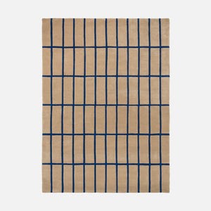 May include: A rectangular beige rug with a grid pattern of dark blue lines. The lines are evenly spaced, creating a modern and geometric design. The rug is made of a soft, textured material.