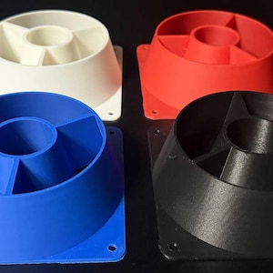 Puede incluir: Cuatro objetos impresos en 3D en blanco, rojo, azul y negro. Cada uno tiene una forma cónica con una abertura central y una base cuadrada con orificios de montaje. Los objetos son probablemente componentes o elementos decorativos.