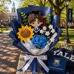 Könnte beinhalten: Ein handgefertigtes Abschluss-Bouquet mit einer gehäkelten Absolventenpuppe mit Hut und Robe, einer gelben Sonnenblume, einer blauen Rose und weißen Blumen. Das Bouquet ist in marineblaues Papier gewickelt und mit einem Band mit der Aufschrift "Herzlichen Glückwunsch!" gebunden. Eine Karte mit dem Wort "Herzlichen Glückwunsch!" ist ebenfalls enthalten.