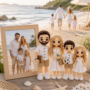 Puede incluir: Un retrato familiar enmarcado descansa sobre una superficie de madera, junto a muñecos de ganchillo que representan a una familia de cuatro. Los muñecos visten trajes blancos y beige. También hay conchas marinas y un salvamanteles de ganchillo. El fondo muestra una escena de playa.