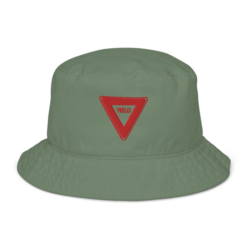 May include: A green bucket hat with a red triangle embroidered on the front. The triangle has the word "YIELD" written inside.