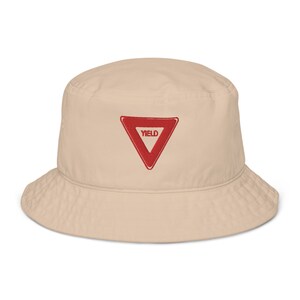 May include: A beige bucket hat with a red triangle and the word "YIELD" embroidered on the front.