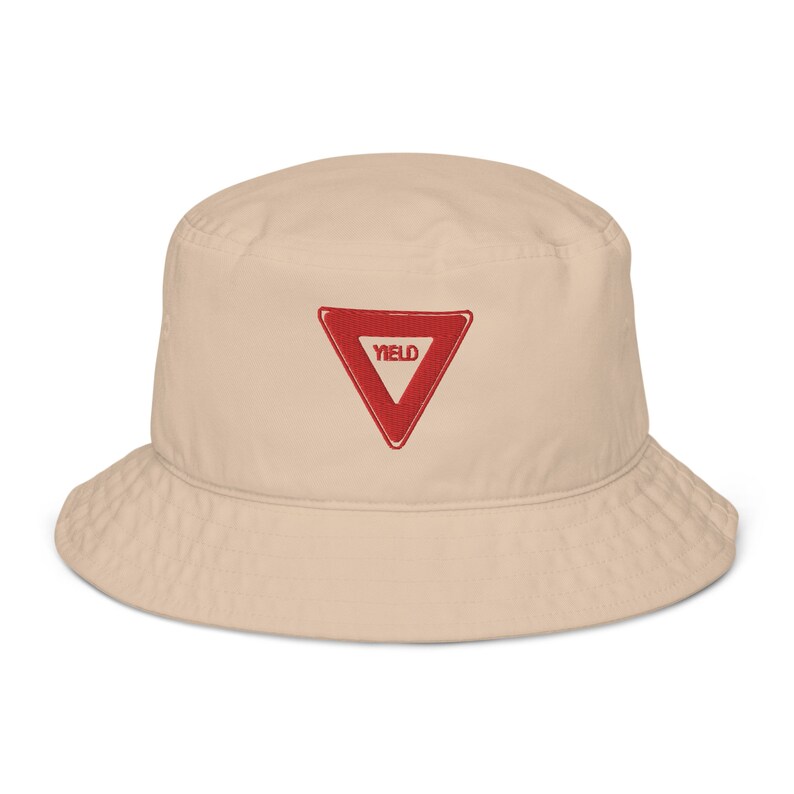 May include: A beige bucket hat with a red triangle and the word "YIELD" embroidered on the front.