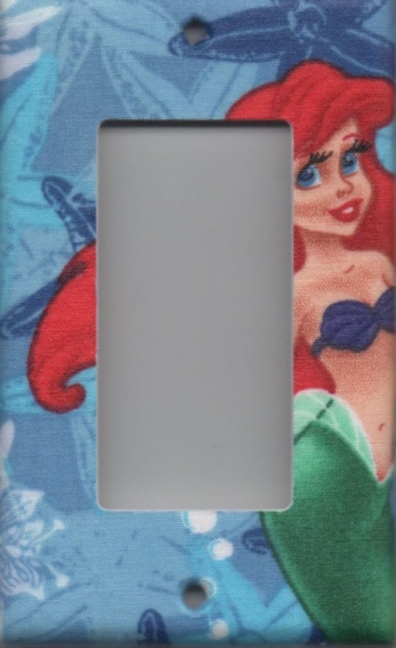 May include: A light switch cover featuring a colourful illustration of Ariel, the Little Mermaid, with a blue, green and white background.