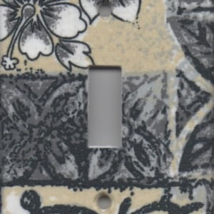 May include: A decorative light switch cover with a floral pattern. The design features white and gray hibiscus flowers on a beige and gray background. The switch opening is a neutral gray color.