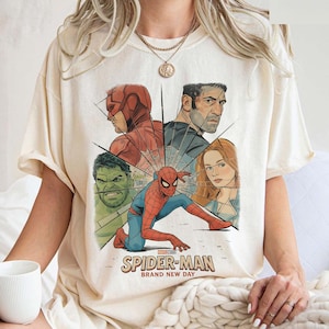 May include: Cream-colored t-shirt featuring a graphic of Spider-Man and other Marvel characters. The design includes the text "SPIDER-MAN BRAND NEW DAY" in a vintage style. The shirt is made of a soft material.