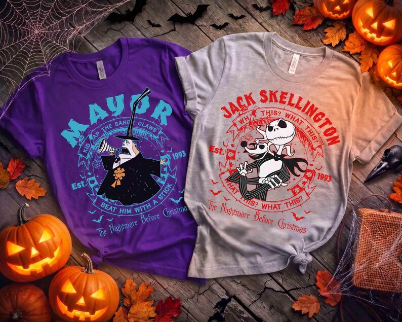 May include: Two t-shirts with Halloween-themed graphics. One is purple with "Mayor" text and a character illustration. The other is gray with "Jack Skellington" text and character art. Pumpkins and leaves surround the shirts.