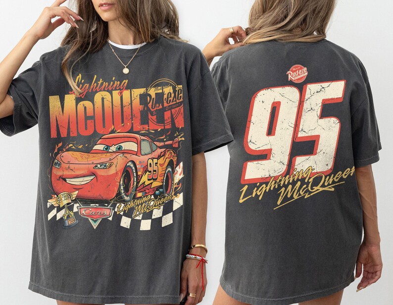 May include: Dark gray Lightning McQueen t-shirt featuring a graphic of the character and the number 95. The front design includes the text "Lightning McQueen" and "Cars". The back of the shirt displays the number 95 and "Lightning McQueen".
