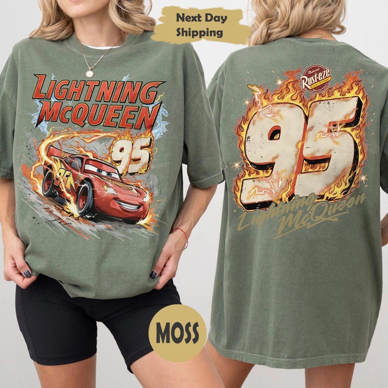 May include: Olive green t-shirt featuring Lightning McQueen from the Cars film. The front graphic shows the car with the number 95 and the text "Lightning McQueen". The back has a large "95" in flames.
