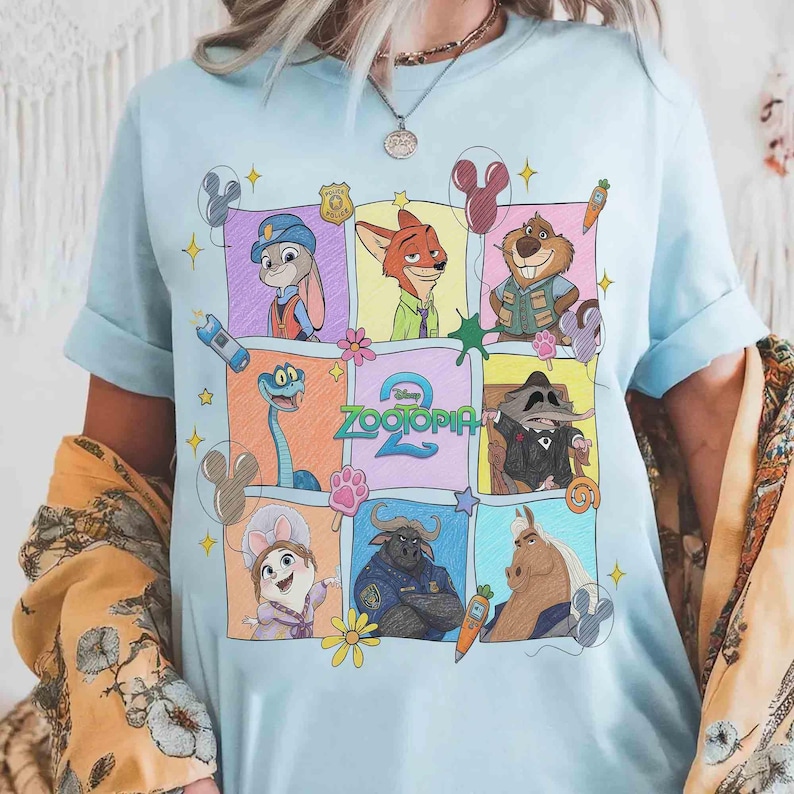 Puede incluir: Camiseta azul claro con un gr&aacute;fico colorido de personajes de la pel&iacute;cula animada "Zootr&oacute;polis". El dise&ntilde;o incluye a Judy Hopps, Nick Wilde y otros personajes en una cuadr&iacute;cula. La palabra "Zootr&oacute;polis" tambi&eacute;n es visible.