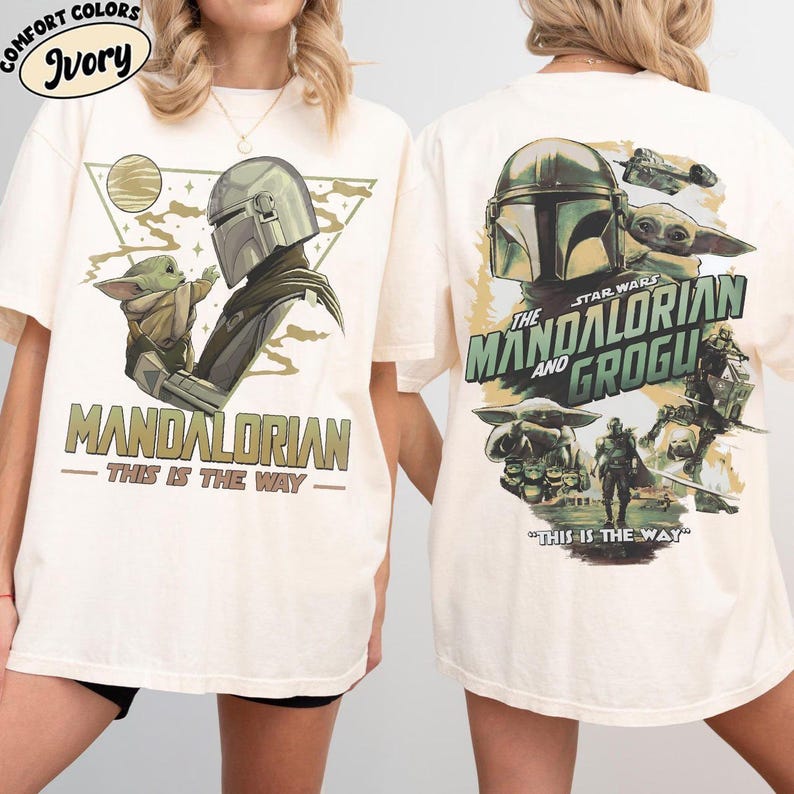 May include: Ivory t-shirts featuring Star Wars characters. The front design shows the Mandalorian and Grogu, with the text "MANDALORIAN - THIS IS THE WAY." The back displays the Mandalorian, Grogu, and other characters, with the text "THE MANDALORIAN AND GROGU - THIS IS THE WAY."