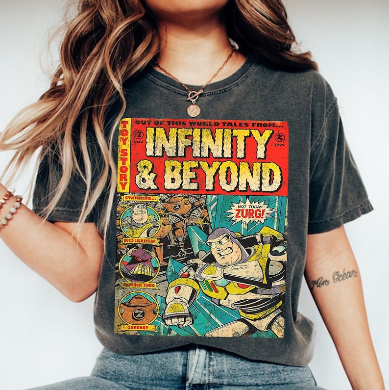 Puede incluir: Camiseta gris oscuro con un dise&ntilde;o de portada de c&oacute;mic. El dise&ntilde;o presenta el texto "INFINITY & BEYOND" en rojo y amarillo, e ilustraciones de Buzz Lightyear y Zurg. Las palabras "TOY STORY" est&aacute;n en el lateral.