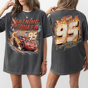 May include: Dark grey Lightning McQueen t-shirt with a graphic of the character and the number 95. The front design shows the red race car with flames, and the back has a large 95 with flames and the text "Lightning McQueen".