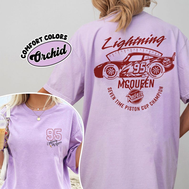 May include: A light purple t-shirt with a graphic of a race car and the text "Lightning McQueen 95". The shirt also features the text "Seven Time Piston Cup Champion". The shirt is a Comfort Colors brand.