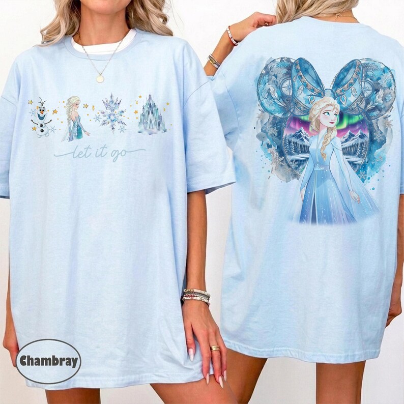 May include: A light blue t-shirt featuring a front graphic with Olaf, Elsa, a snowflake, and an ice castle with the text "let it go". The back graphic displays Elsa centred within a large blue Mickey Mouse ear silhouette filled with winter scenery.