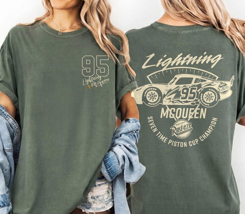 May include: Olive green t-shirt featuring the number 95 and the words "Lightning McQueen" on the front. The back of the shirt displays a graphic of a race car with the text "Lightning McQueen" and "Seven Time Piston Cup Champion".