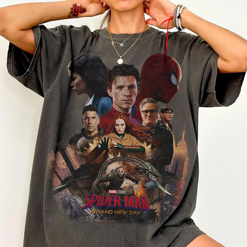 May include: Dark gray t-shirt featuring a movie poster design with multiple characters, including Spider-Man. The text "SPIDER-MAN BRAND NEW DAY" is prominently displayed. The shirt has a vintage, worn look.
