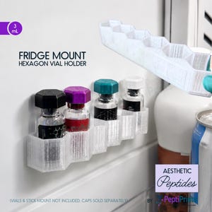 May include: A white 3D-printed hexagon fridge mount vial holder with five slots. Four small glass vials with black, purple, teal, and white caps are inserted into the holder. Text reads: FRIDGE MOUNT HEXAGON VIAL HOLDER, 3 mL, and AESTHETIC Peptides.