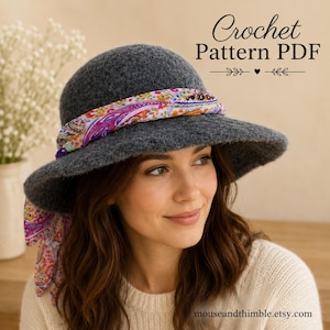 May include: A dark gray felted cloche hat with a wide brim, adorned with a colorful floral and paisley patterned fabric scarf tied around the crown. The text Crochet Pattern PDF is visible in the upper right corner of the image.