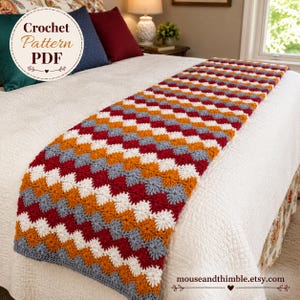 May include: A rectangular crochet bed runner featuring a repeating geometric pattern in alternating rows of dark red, white, orange, and grey yarn. The text Crochet Pattern PDF is visible in the upper left corner, and mouseandthimble.etsy.com is at the bottom.