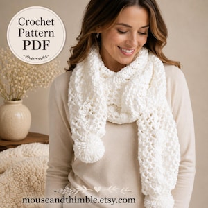 Op de afbeelding: Een witte gehaakte sjaal met een gestructureerd opengewerkt patroon en grote pompons aan beide uiteinden. Een cirkelvormige afbeelding in de linkerbovenhoek toont de tekst Crochet Pattern PDF, en onderaan staat de tekst mouseandthimble.etsy.com.